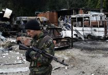 Ополченец рядом с автомобилями, поврежденными во время артобстрела Донецка Ополченец рядом с автомобилями, поврежденными во время артобстрела Донецка