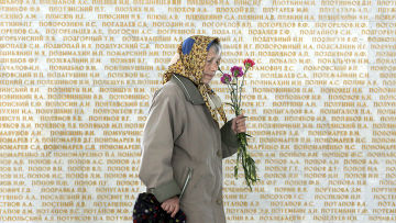 Женщина на фоне стены с именами погибших в Великой отечественной войне в Киеве