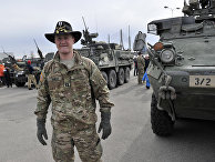 Капитан американской армии возле боевой бронированной машины «Страйкер» Капитан американской армии возле боевой бронированной машины «Страйкер»