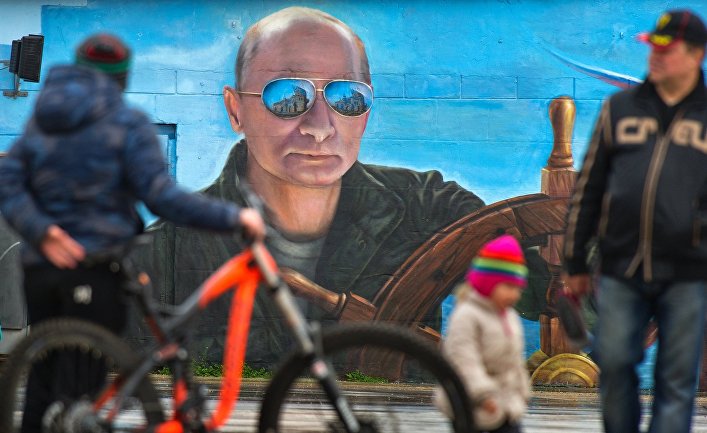 Прохожие у портрета президента России Владимира Путина на стене здания в Ялте