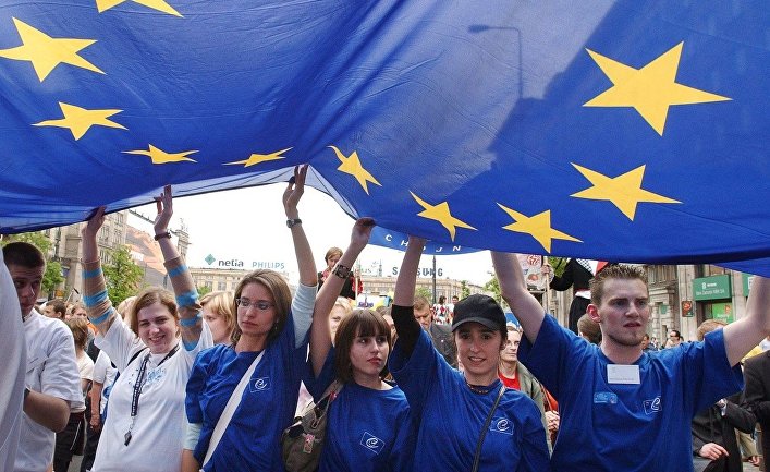 Молодые люди несут флаг Европейского союза во время парада Шумана в Варшаве