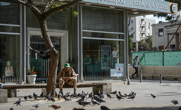 Мужчина кормит голубей у закрытого офиса Bank of Cyprus в Никосии