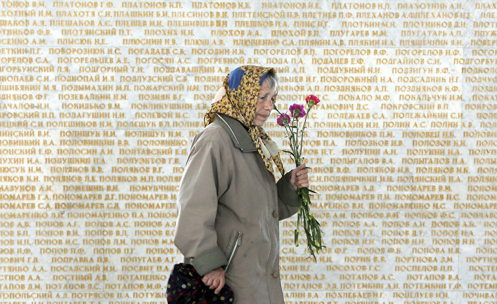 Женщина на фоне стены с именами погибших в Великой отечественной войне в Киеве