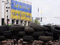 Оставшиеся после акций сторонников Евроинтеграции баррикады из автомобильных покрышек и национальный флаг Украины с надписью "Единая страна" на русском и украинских языках Оставшиеся после акций сторонников Евроинтеграции баррикады из автомобильных покрышек и национальный флаг Украины с надписью "Единая страна" на русском и украинских языках