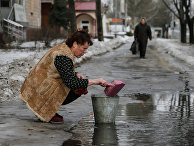 Женщина в Донецке набирает воду из лужи Женщина в Донецке набирает воду из лужи