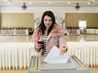 Девушка опускает бюллетень в урну на выборах президента РФ на избирательном участке в Бахчисарае. 18 марта 2018