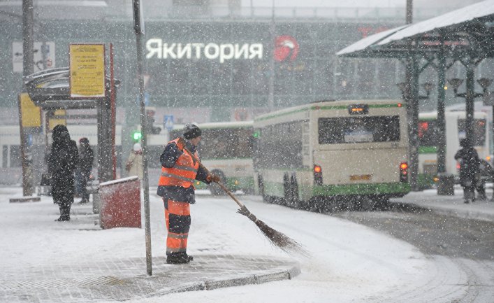 Работник коммунальной службы убирает снег с тротуара на остановке общественного транспорта в районе станции метро Щукинская в Москве