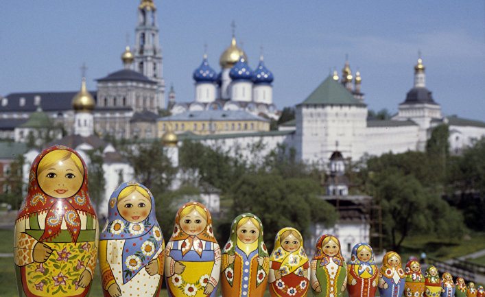 Русские матрешки, сфотографированные на фоне Троице-Сергиевой лавры