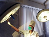 Медицинская сестра устанавливает свет в операционной Медицинская сестра устанавливает свет в операционной