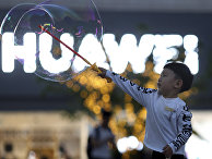 Мальчик играет с мыльными пузырями возле магазина Huawei в Пекине Мальчик играет с мыльными пузырями возле магазина Huawei в Пекине