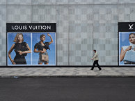 Мужчина идет мимо магазина Louis Vuitton в Ухане, Китай Мужчина идет мимо магазина Louis Vuitton в Ухане, Китай