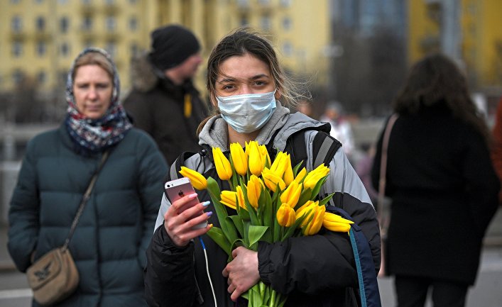 Девушка с цветами и в маске на Пушкинской набережной в Парке Горького в Международный женский день в Москве