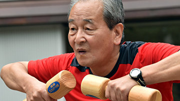 Пожилой мужчина во время занятий с деревянными гантелями в Токио
