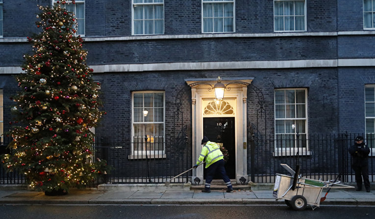 Уборщик подметает перед дверью резиденции премьер-министра Великобритании на Даунинг-стрит, 10, Лондон
