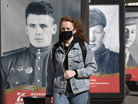 Женщина в маске идет мимо плакатов с портретами солдат Великой Отечественной войны Женщина в маске идет мимо плакатов с портретами солдат Великой Отечественной войны