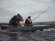 Русская женщина ловит рыбу в компании медведя Русская женщина ловит рыбу в компании медведя